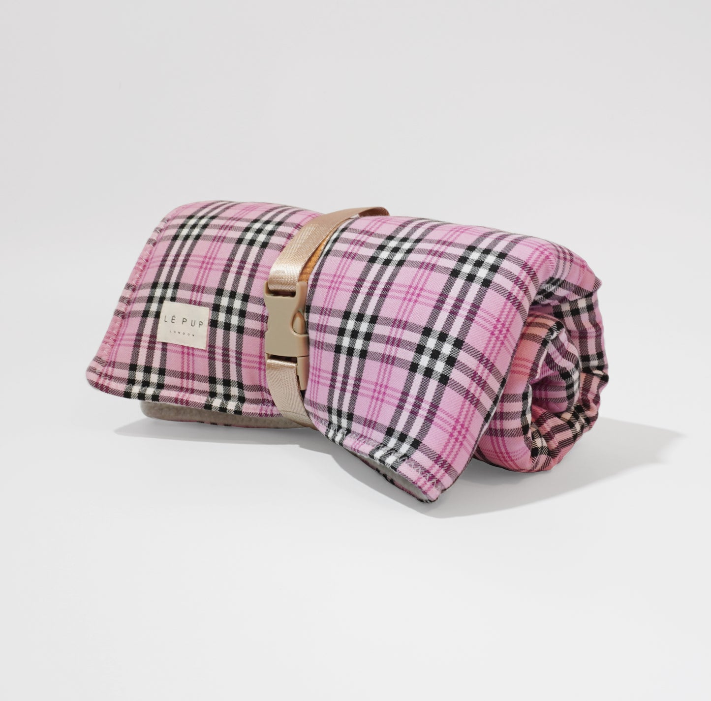 Side view of pink tartan rolled up travel dog mat with handle strap by LE PUP