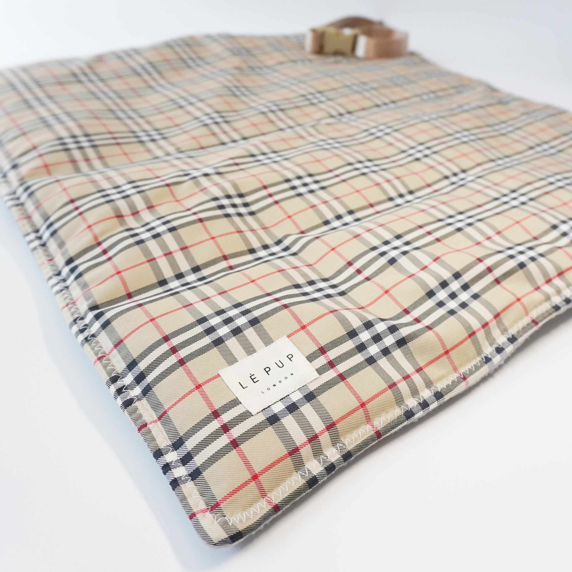 Close up of foldable dog travel mat laid out in tartan print with removable strap by LE PUP.